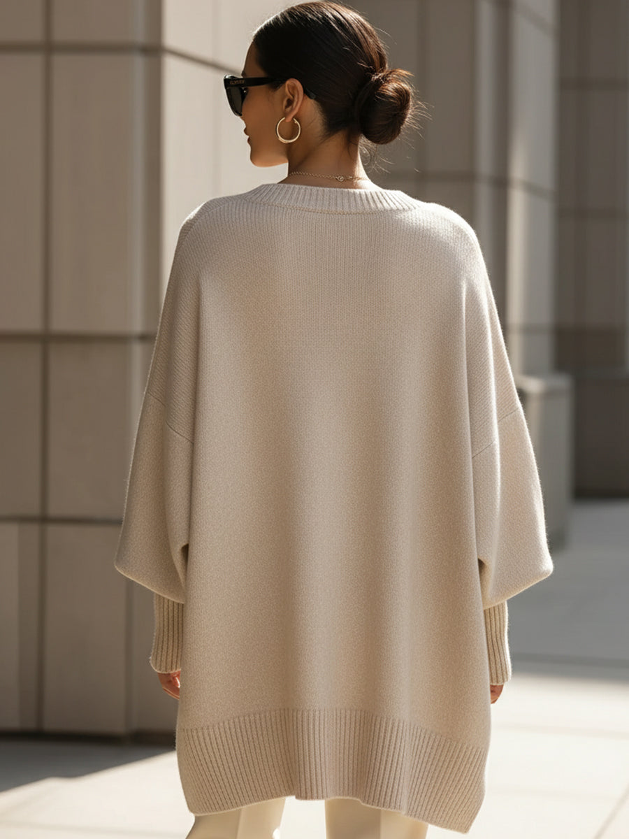 Woman wearing an oversized poncho sweater with asymmetric ribbed hem and mock neck