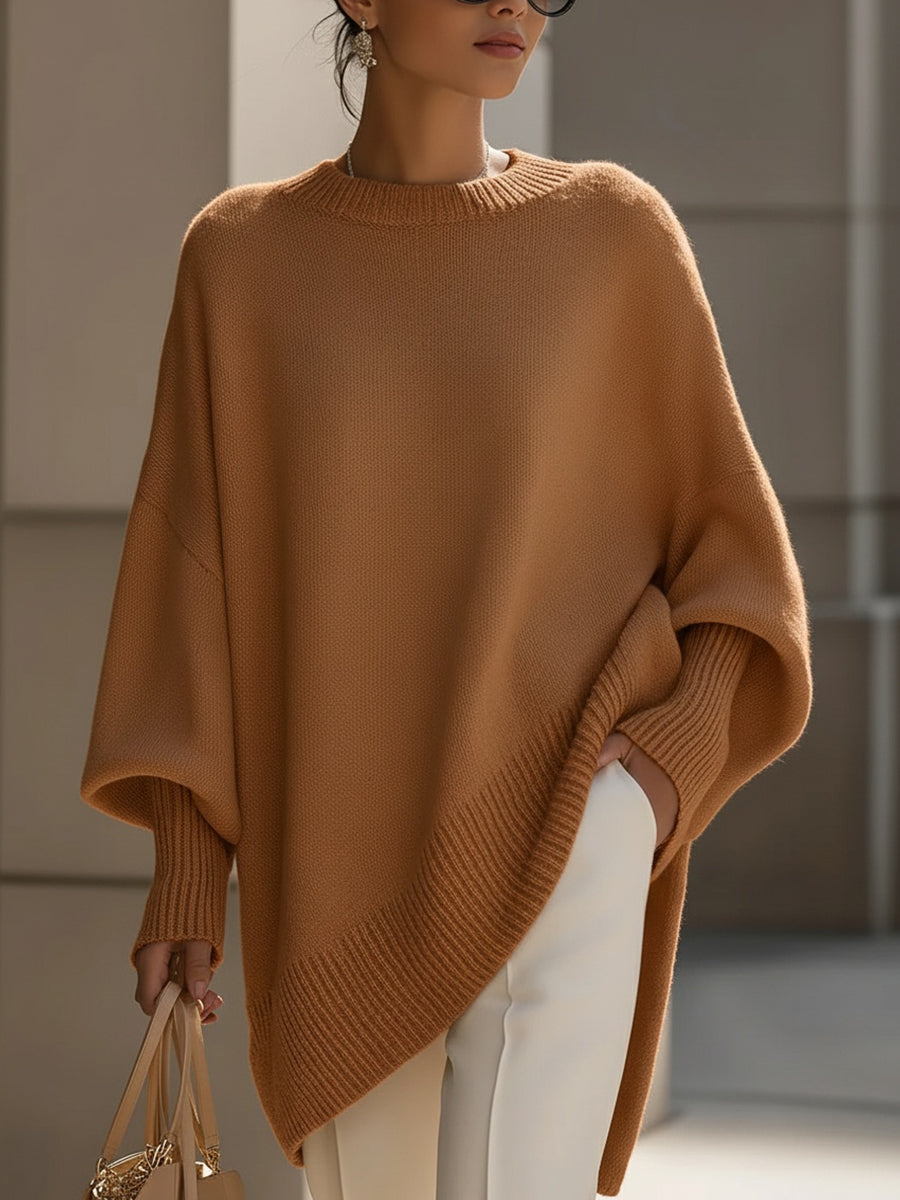 Woman wearing an oversized poncho sweater with asymmetric ribbed hem and mock neck