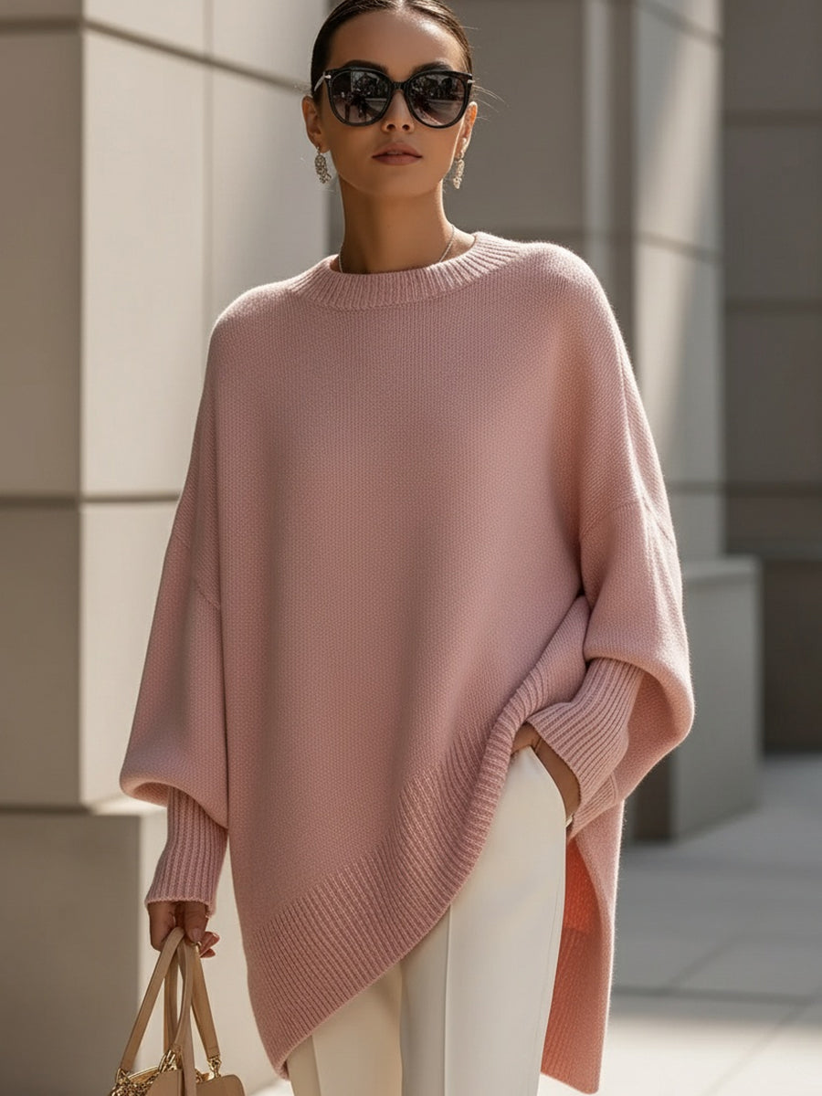 Woman wearing an oversized poncho sweater with asymmetric ribbed hem and mock neck