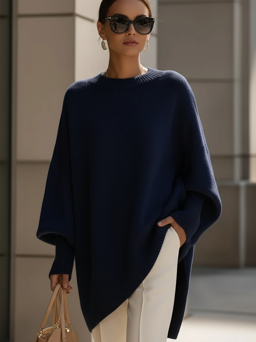 Woman wearing an oversized poncho sweater with asymmetric ribbed hem and mock neck