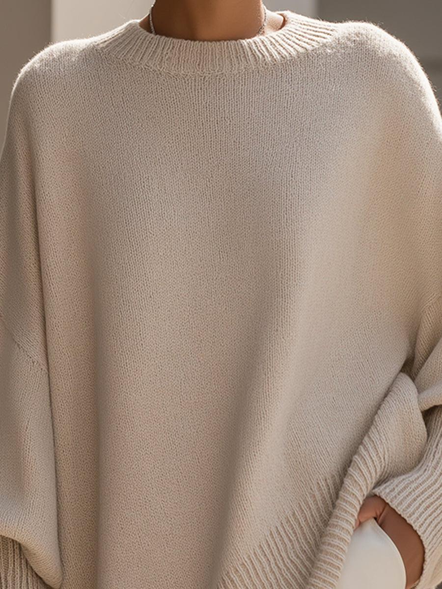 Woman wearing an oversized poncho sweater with asymmetric ribbed hem and mock neck