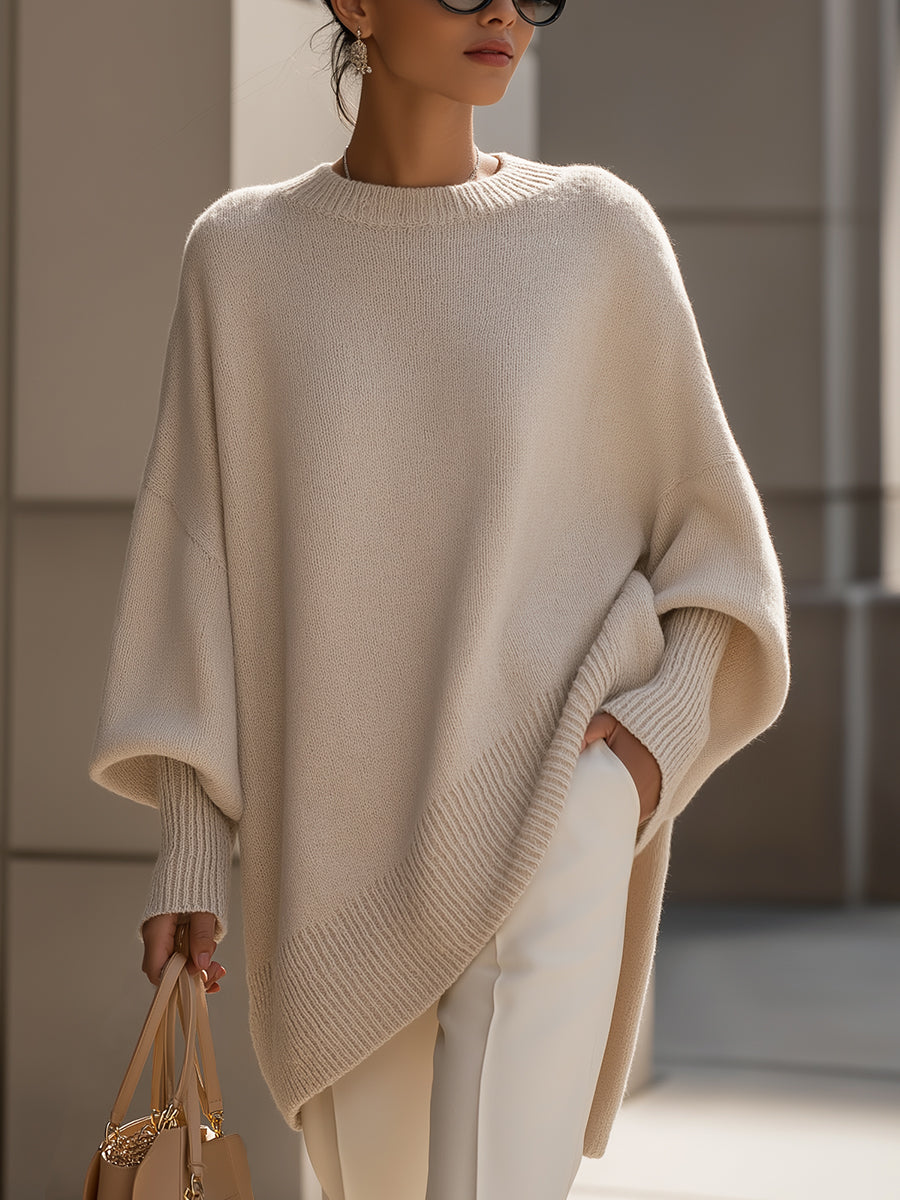 Woman wearing an oversized poncho sweater with asymmetric ribbed hem and mock neck