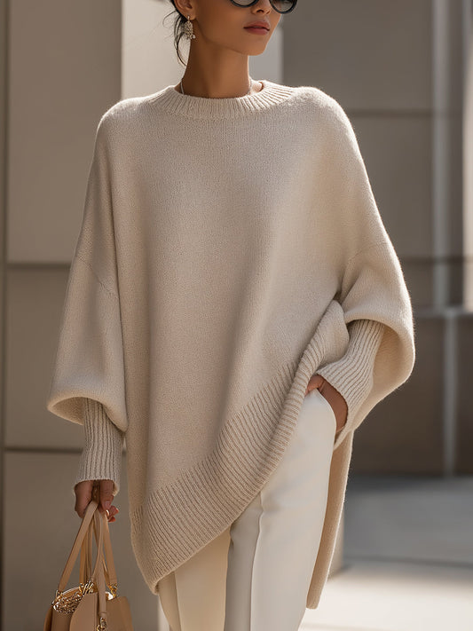 Woman wearing an oversized poncho sweater with asymmetric ribbed hem and mock neck