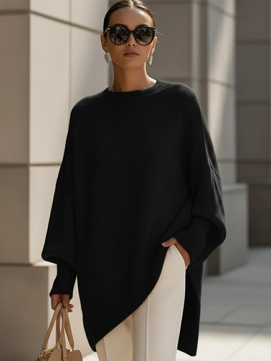Woman wearing an oversized poncho sweater with asymmetric ribbed hem and mock neck