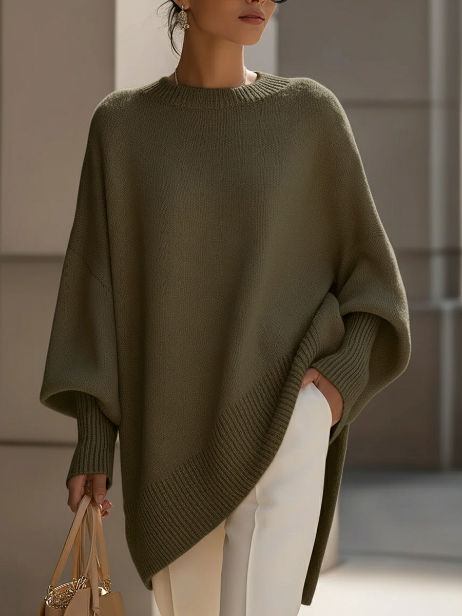 Woman wearing an oversized poncho sweater with asymmetric ribbed hem and mock neck