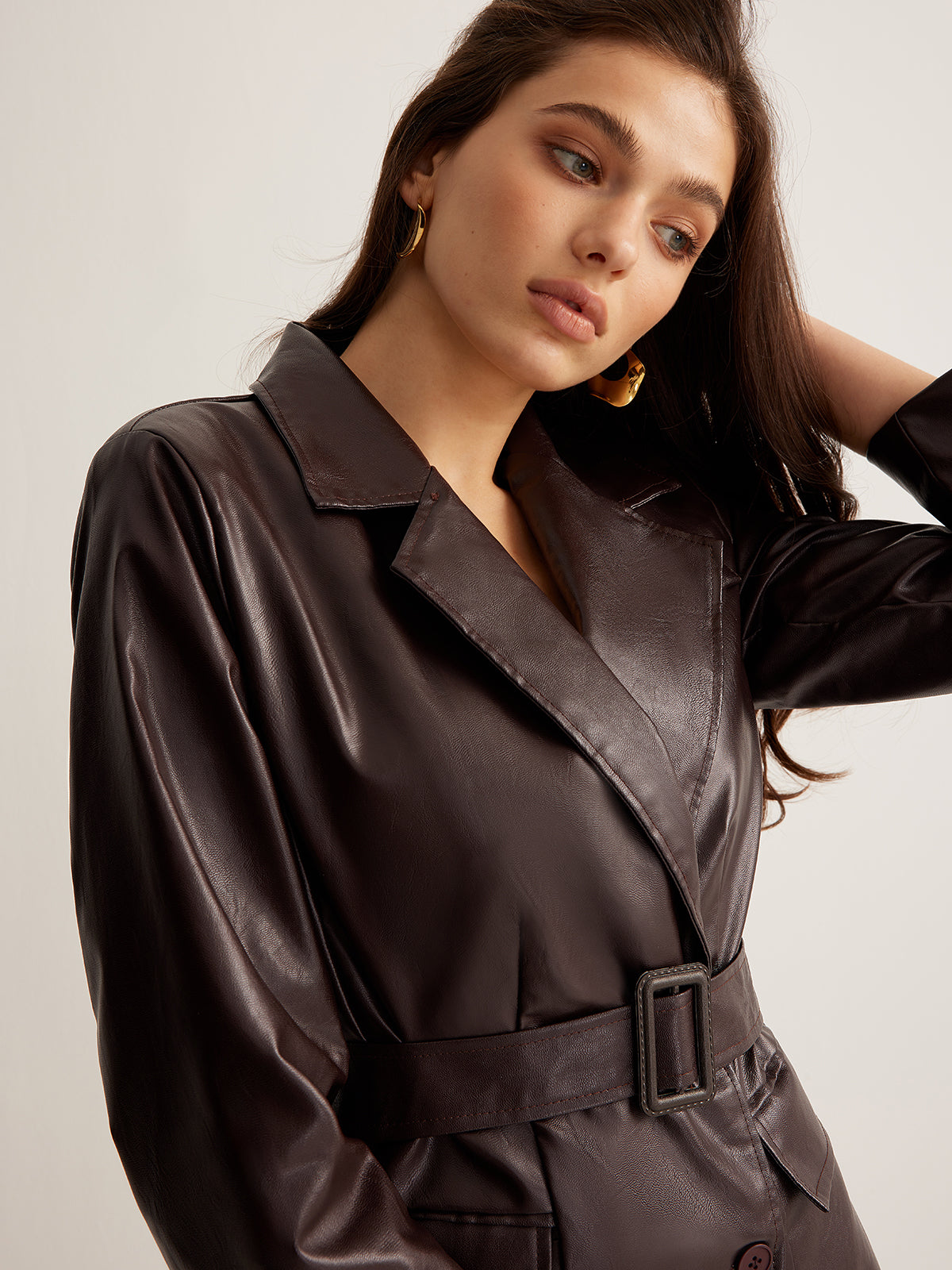 Woman wearing a belted burgundy faux leather jacket