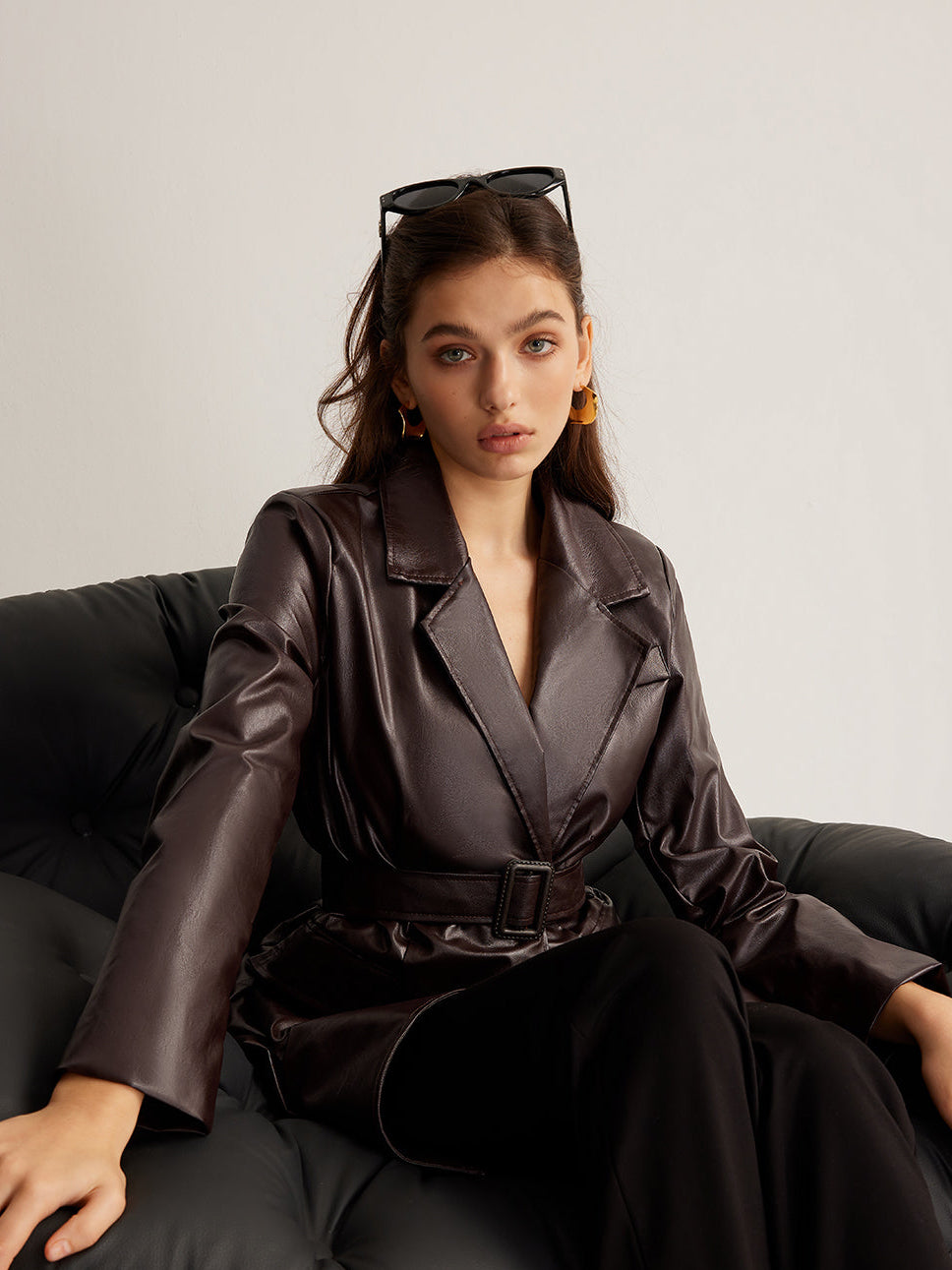 Woman wearing a belted burgundy faux leather jacket
