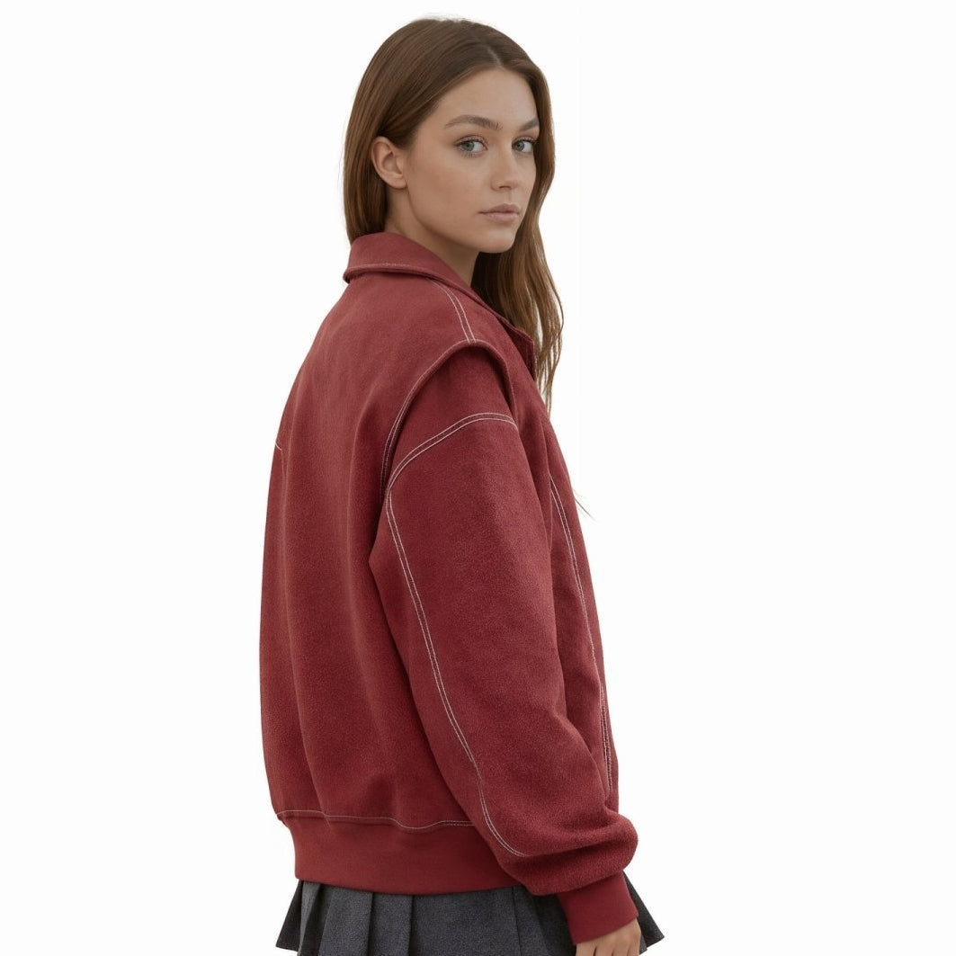 Woman wearing an oversized red faux leather bomber jacket with white contrast stitching