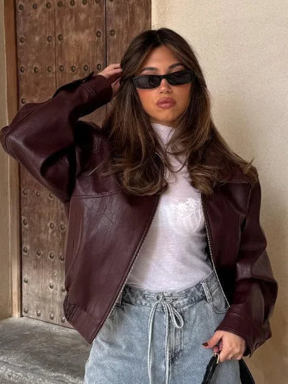Woman wearing an oversized cropped faux leather jacket with a stand collar and zip front