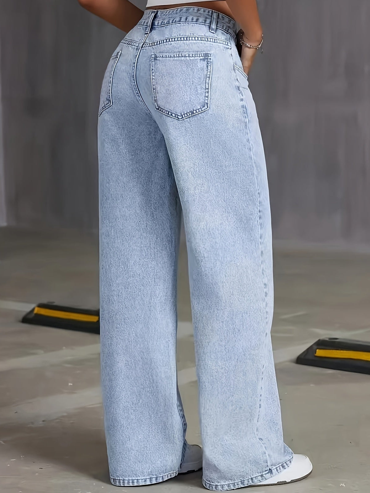 Woman wearing high waisted light wash wide leg jeans with five pocket styling